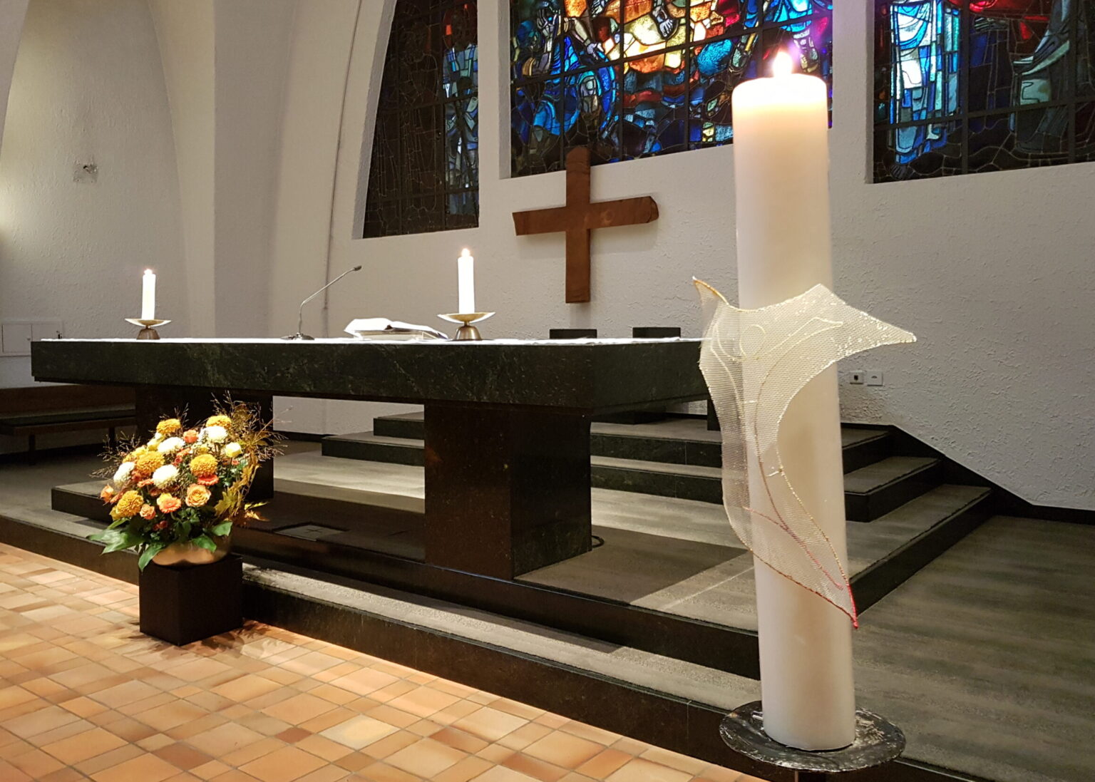Altar der Kirche St. Martin für den Gottesdienst vorbereitet. Die Kerzen brennen, die Osterkerze ist im Vordergrund und vor dem Altar steht ein wunderschönes Herbstbouquetndmit Osterkerze und Herbst