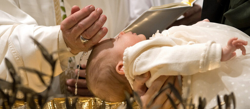 Kleinkind wird über einem goldenen Taufbecken von Papst Franziskus getauft